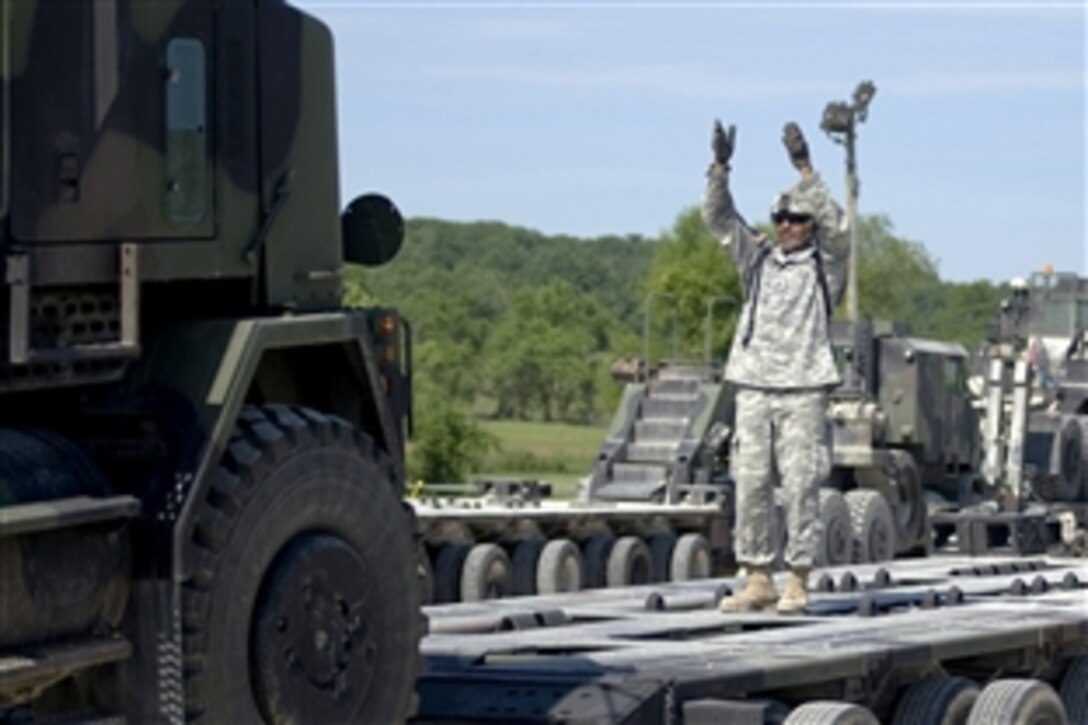 U.S Army Sgt. Christopher Carter signals to the driver of a Heavy Equipment Transport, or HET, as they load it onto a trailer while preparing for convoy operations during training at Camp Atterbury, Joint Maneuver Training Center, Ind., June 20, 2008.  

