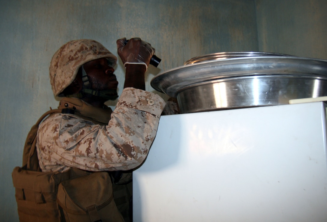 Lance Cpl. Nyan Baar, a 2/25 Reserve Marine, peers into a container atop a refrigerator, searching for explosive-making materials or other evidence at the home of a suspected insurgent during a training exercise here June 26, 2008.  A native of Penbrook, Mass. and a mental health worker in his civilian career, Baar joined 2/25 in February as an individual augment for their upcoming deployment to Iraq.