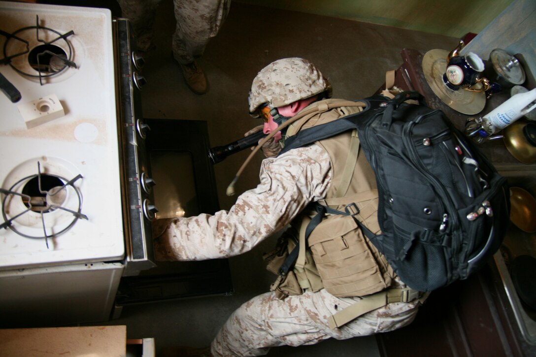 Lance Cpl. Sean Burke, a Reserve Marine from Company E, 2/25, searches inside a stove for hidden explosive equipment during a training exercise here June 26, 2008.  A select group of reserve Marines bound for Iraq came to the Joint Center of Excellence's Search and Tactical Site Exploitation course as part of their predeployment training.  Burke put his junior year of college at Temple University on hold for his first deployment overseas.