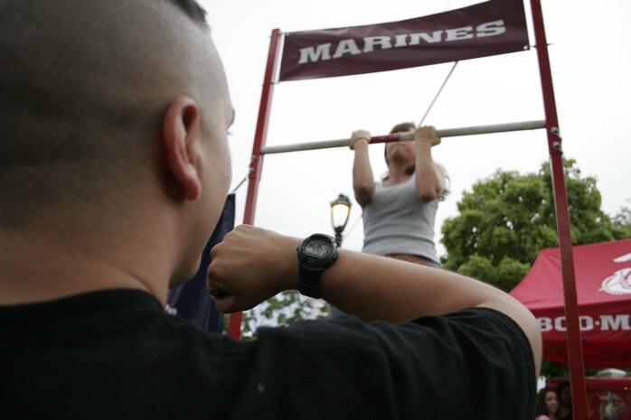 Sgt. Levi Moran times a participant performing the flexed-arm hang at Summerfest June 26. Marines challenged the music festival attendees to either perform a max set of pull-ups or a flexed-arm hang as long as possible to raise awareness of the Marine Corps. Moran is a recruiter for recruiting sub-station North Milwaukee .