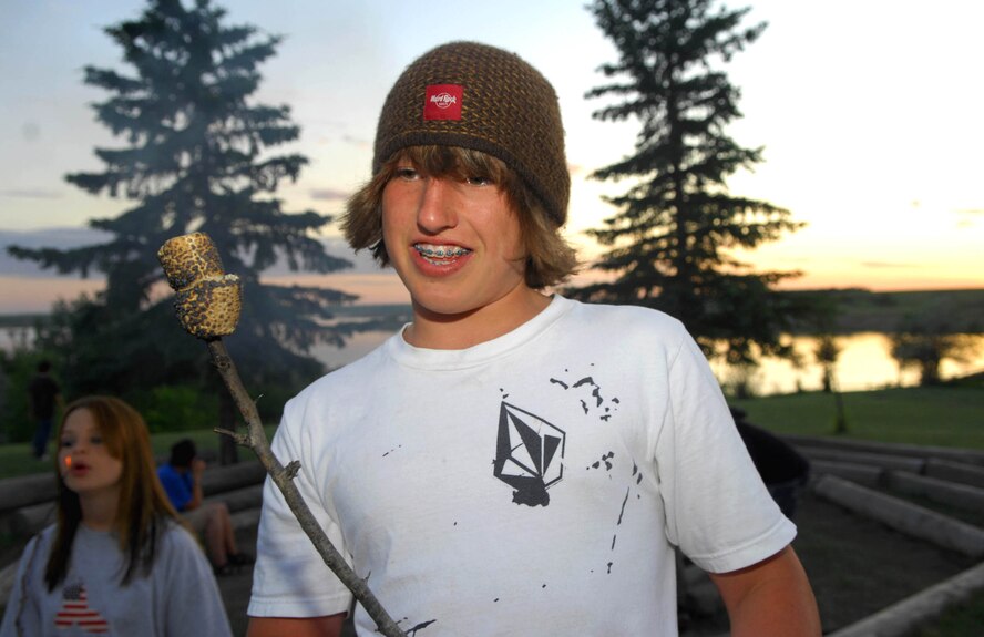 MINOT AIR FORCE BASE, N.D. -- Mikey Lilly, son of Master Sgt. Wendy Lilly, 54th Helicopter Squadron, relaxes by the camp fire while enjoying a roasted marshmallow at Y Camp. Youth from Minot Air Force Base attended a youth camp hosted by the 5th Force Support Squadron and the Minot AFB Youth Center June 20 through June 22 at the Y Camp near Garrison, N.D. 