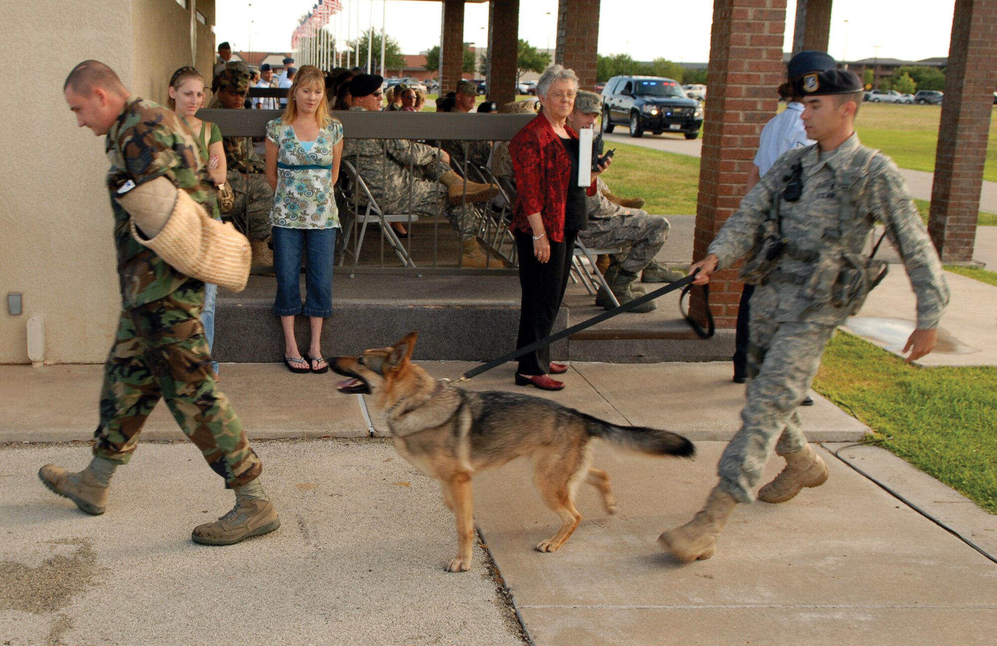 Staff Sergeant Dustin Vigil, 17th Security Forces Squadron, is led away during the military working dog demonstration at the July 20 Pass in Review, as Military Working Dog Ema ensures he doesn’t make any sudden movements. Also escorting Sergeant Vigil is MWD Ema’s handler, Staff Sgt. Christopher Bauer. MWD Ema has been at Goodfellow for two years, and returned from deployment in February. (U.S. Air Force photo by Staff Sgt. John Barton)