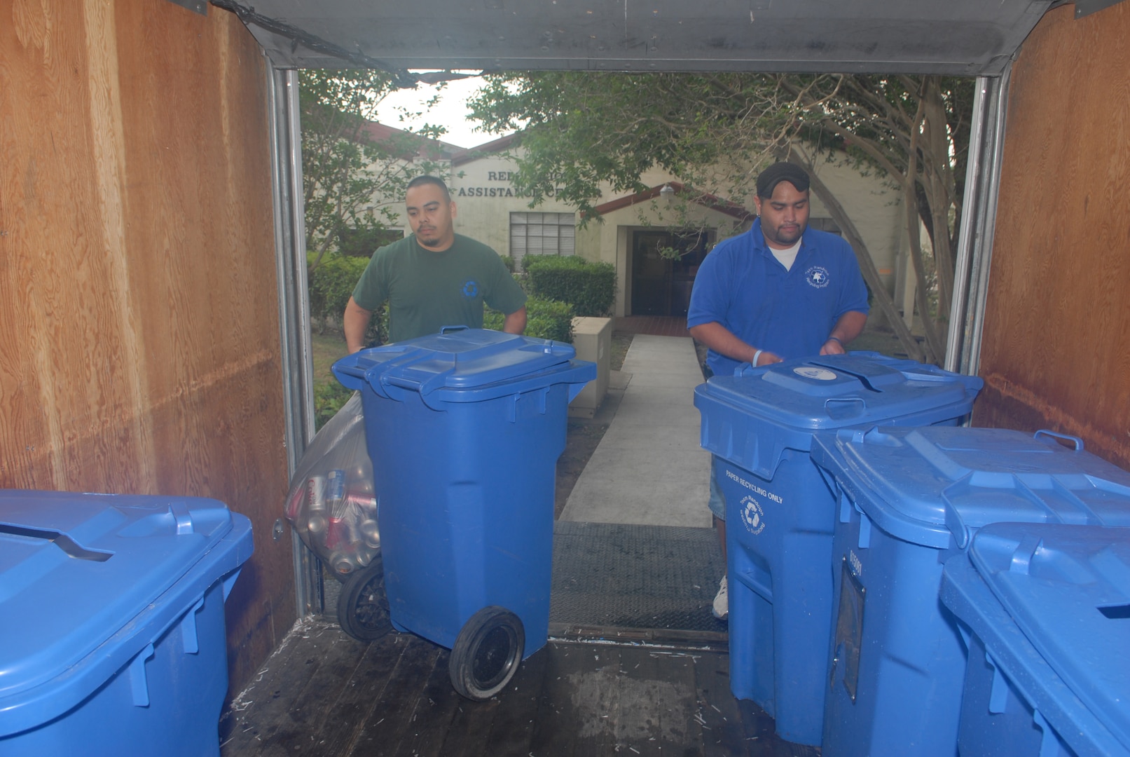 Henry Guadarrama (left) and Rene Hernandez, both base recycling crew members, work together recently at the Family Support Center here to collect recyclables from the blue recycling bins located there. (U.S. Air Force photo by Don Lindsey)