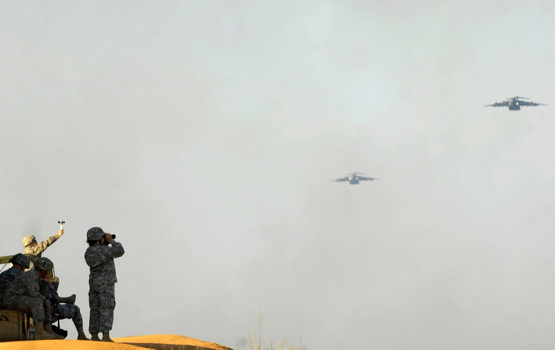 Army Soldiers watch as two C-17 Globemaster IIIs prepare to drop paratroopers during Joint Forcible Entry Exercise June 18 at Fort Bragg, N.C. The Joint Forcible Entry Exercise is a joint airdrop designed to enhance service cohesiveness between Army and Air Force members, allowing both services an opportunity to properly execute large-scale heavy equipment and troop movement.  (U.S. Air Force photo/Staff Sgt. Rasheen A. Douglas)