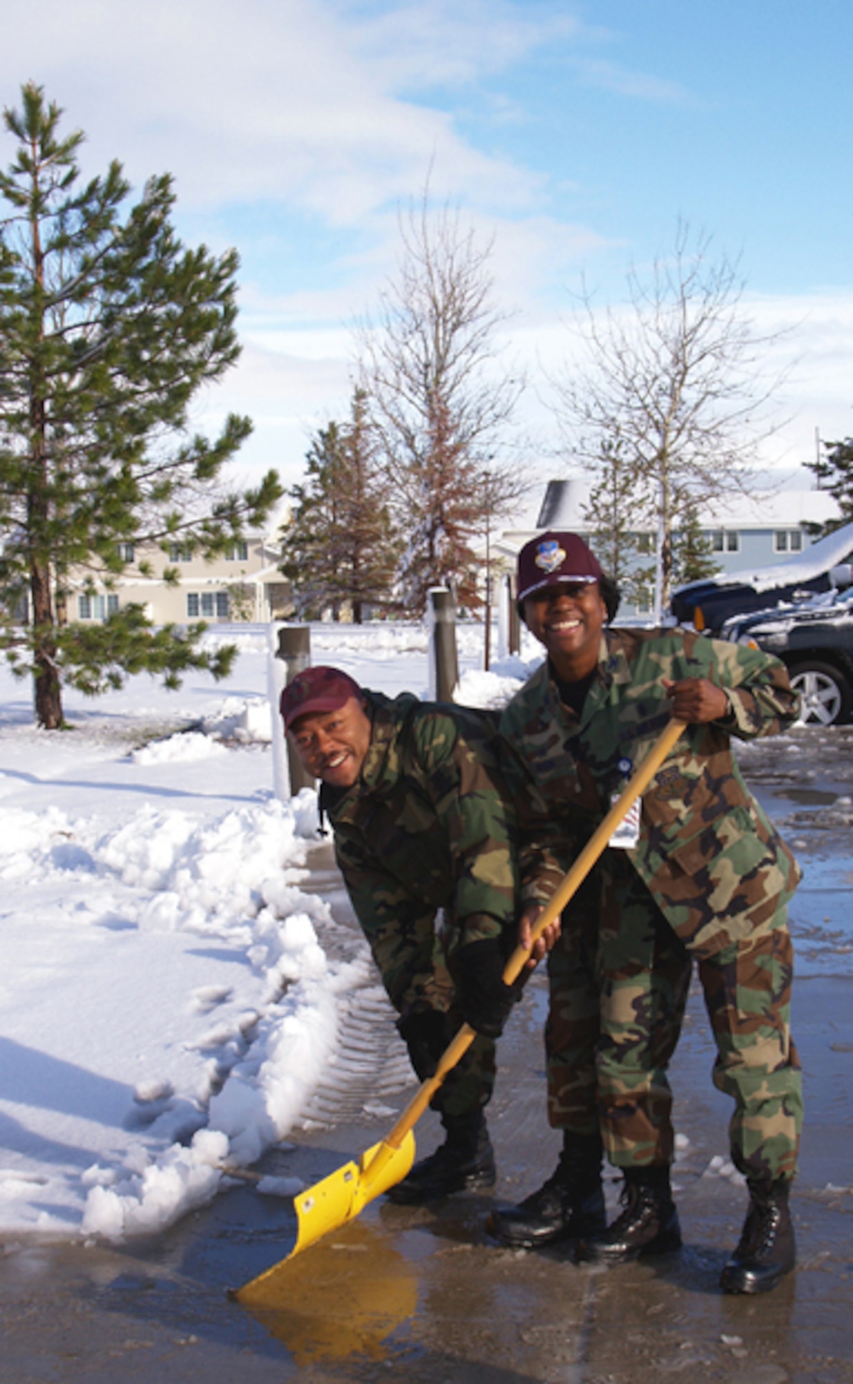 Col. Leslie Dixon, 341st Medical Group commander, and Master Sgt. Melvin Skyes, 341st Medical Support Squadron, shovel  outside the clinic after being surprised with a snowstorm June 11. (Courtesy photo)