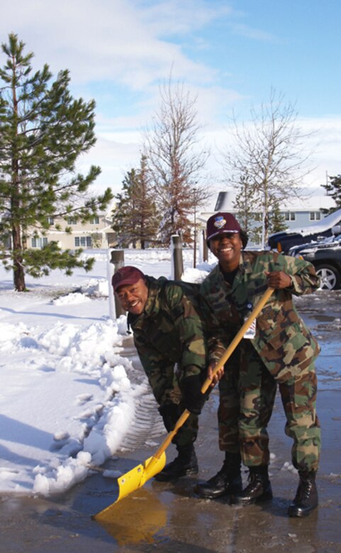 Col. Leslie Dixon, 341st Medical Group commander, and Master Sgt. Melvin Skyes, 341st Medical Support Squadron, shovel  outside the clinic after being surprised with a snowstorm June 11. (Courtesy photo)