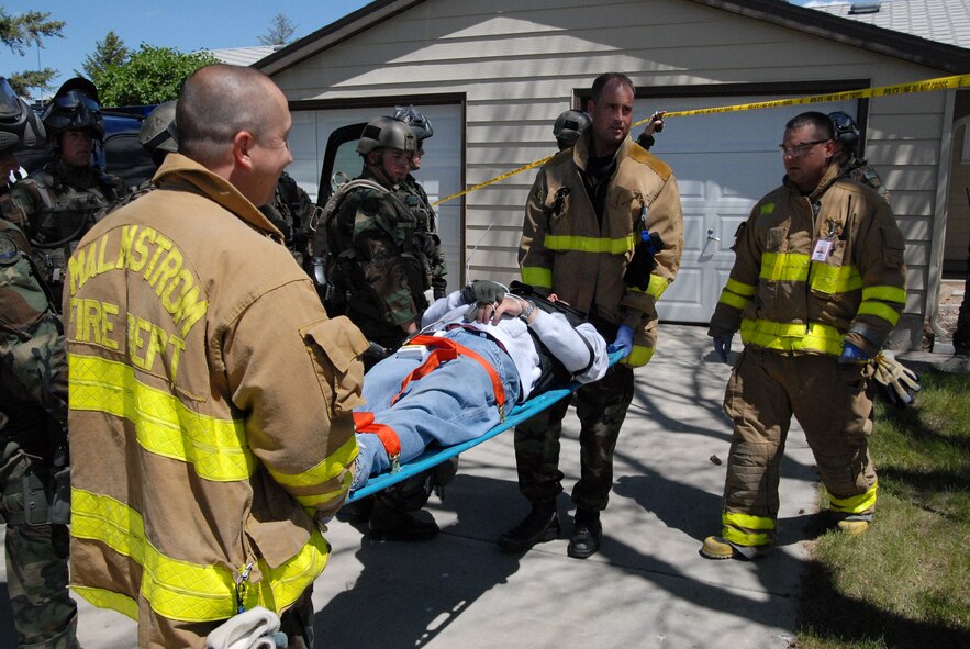 Tech. Sgt. Jason McMichael and Staff Sgt. Michael Johns, 341st Civil Engineer Squadron firefighters, transport an injured victim to the medical support team for transportation to the hospital, while Staff Sgt. Gregory Demarco, 341st CES firefighter, looks on during an exercise June 23. The exercise consisted of responding to a hostage situation in the housing area on base. (U.S. Air Force photo/John Turner)