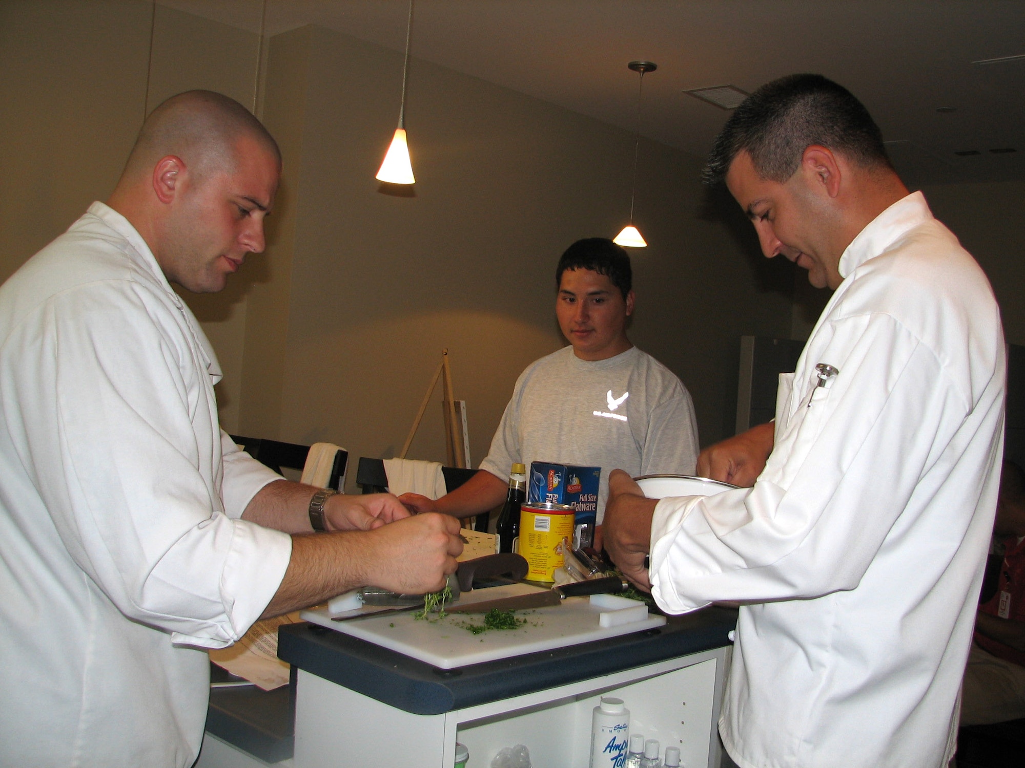 Tech. Sgt. Jason Simas and Staff Sgt. Michael Leo prepare a meal for Airmen at the Center for the Intrepid June 24 in San Antonio. Airman 1st Class Kevin Krogh assists in the preperation. The sergeants are enlisted aides to the Air Education and Training Command commander and vice commander. They volunteered their culinary talents to support sevicemembers in treatment at the center. (U.S. Air Force photo/Beverly Simas) 
