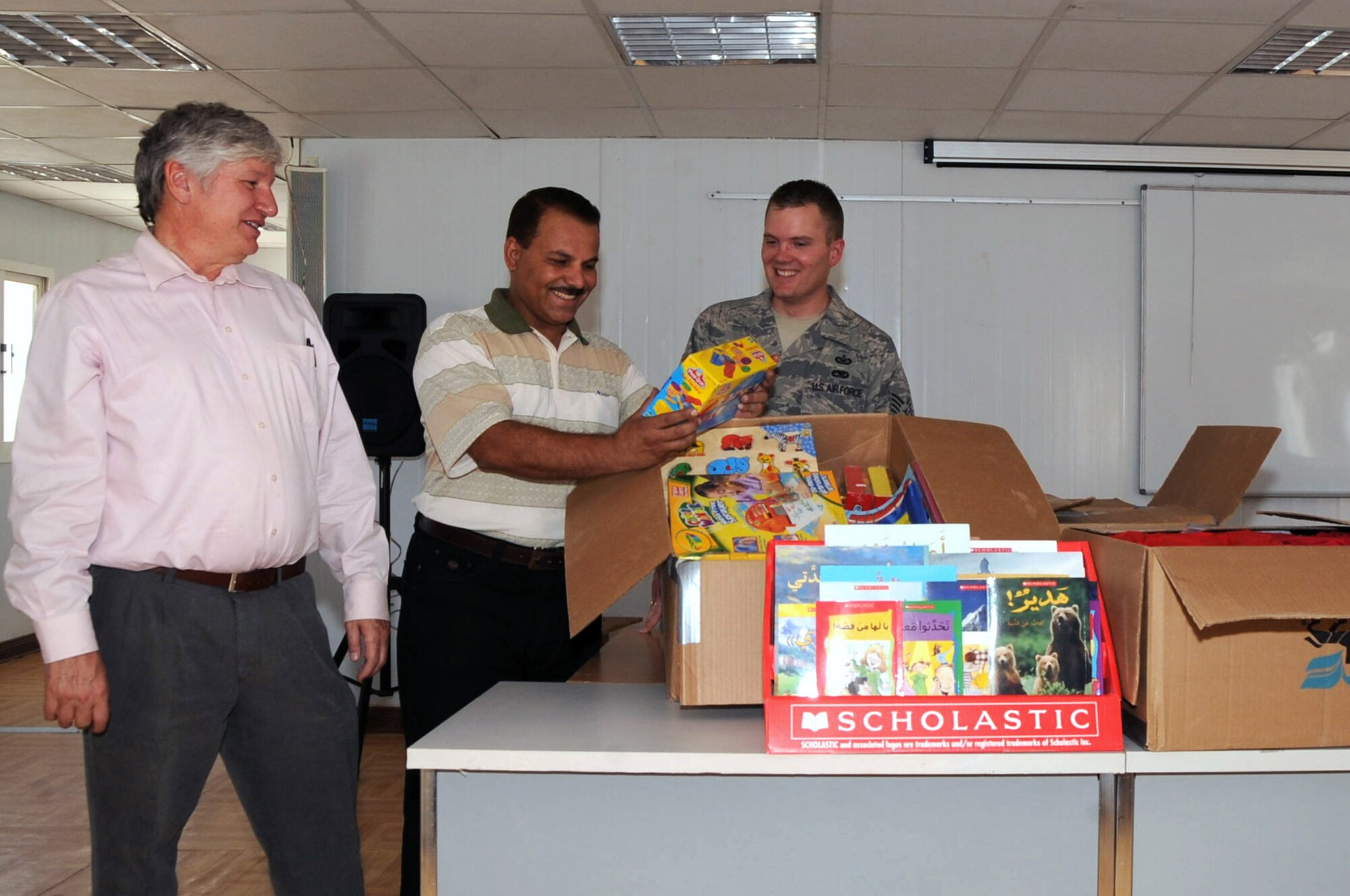 ALI BASE, Iraq -- Staff Sgt. Nathan Gallahan, Focus 5/6 Council representative, and John Dorshner, Provincial Reconstruction Team public relations manager, hand over school supplies and clothing donated from organizations, families and individuals from around the United States to a representative from the Iraqi Department of Education here June 27. The Focus 5/6 Council is an independent professional organization made up of Air Force staff and technical sergeants, that strives to advance junior NCOs into active roles that will enhance themselves, the base and the local Iraqi Community. Sergeant Gallahan is deployed to the 407th Air Expeditionary Group from RAF Lakenheath, United Kingdom. (U.S. Air Force photo/Tech. Sgt. Sabrina Johnson)