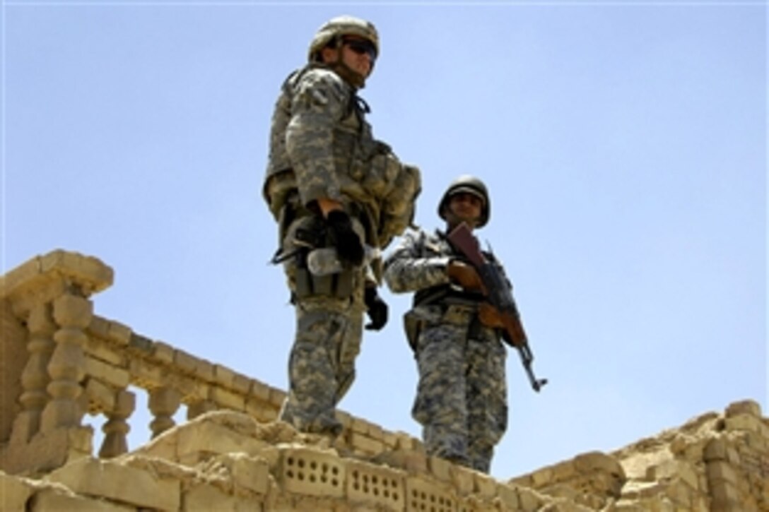 U.S. Army 1st Lt. Foster Thorpe, left, and an Iraqi National Police officer stand on top of an abandoned house during a cordon and search operation in Al Batta, Iraq, June 20, 2008.