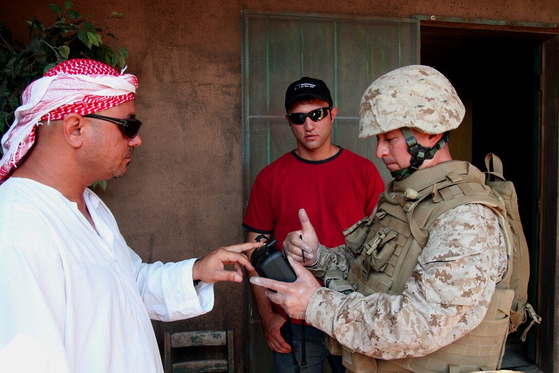 Staff Sgt. Jim Angulo from Headquarters and Service Company, 2nd Battalion, 25th Marine Regiment uses the Handheld Interagency Identification Detection Equipment device to record the fingerprints of an inhabitant of a house where his squad found explosive-making materials during a training exercise here June 27, 2008.  Angulo is assisted by an Iraqi interpreter (rear).  The HIIDE, which records and stores biometrics data, is currently used in Iraq and Afghanistan to identify and apprehend insurgents and other suspected criminals.  A reserve Marine and New York City police officer, Angulo is preparing for his second tour in Iraq.