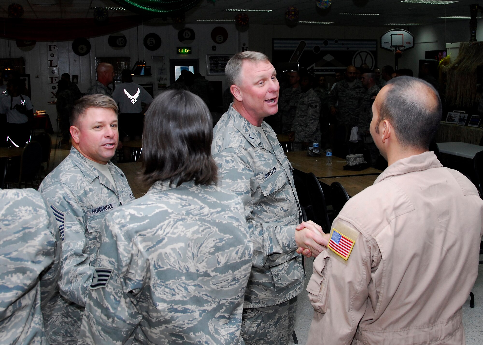 SOUTHWEST ASIA -- Colonel Robert Swisher, (center), 386th Air Expeditionary Wing commander and Chief Master Sgt. Carl Hunsinger, (left), 386th AEW command chief, shake the hands of some of the 67 wing Airmen selected for promotion to master and technical sergeant following a ceremony here June 27. (U.S. Air Force photo/Staff Sgt. Patrick Dixon)