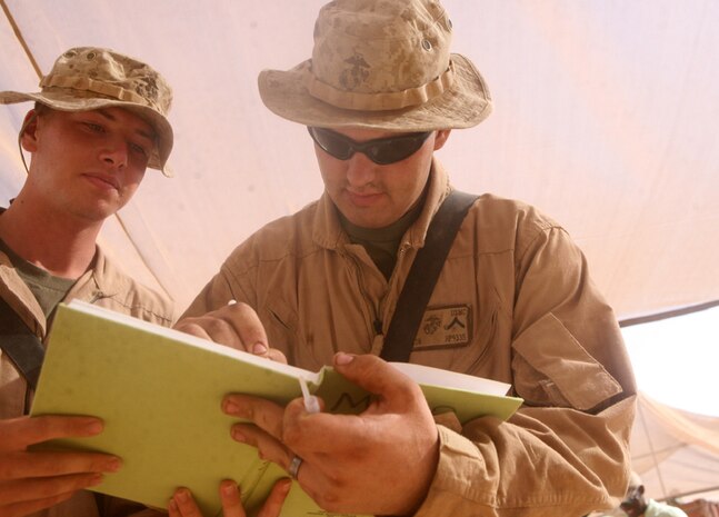 Pfc. Jonathan R. Payton (right), a motor vehicle operator, and Pfc. Brian D. Ahern, a field radio operator, both with Headquarters and Service Company, 2nd Light Armored Reconnaissance Battalion, Regimental Combat Team 5, sign the initial log for the grand opening of the new internet and phone center at Camp Korean Village, Iraq, June 28. The two Marines were the first to get to use the new center, which has more than 16 computers and 10 phones for service members to use.::r::::n::