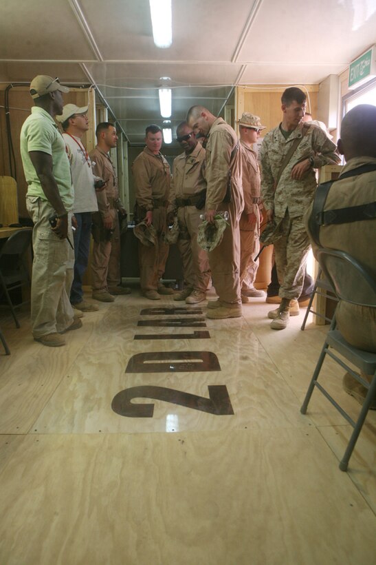 Gazing at the "2D LAR" painted on the new internet and phone center floor, Marines with 2nd Light Armored Reconnaissance Battalion, Regimental Combat Team 5, and civilian contractors tour the new center at Camp Korean Village, Iraq, June 28. The center was named after Gunnery Sgt. Curtis T. Rinker, company gunnery sergeant, Headquarters and Service Company, 2nd LAR after his hard work on the month-long project to build it.::r::::n::