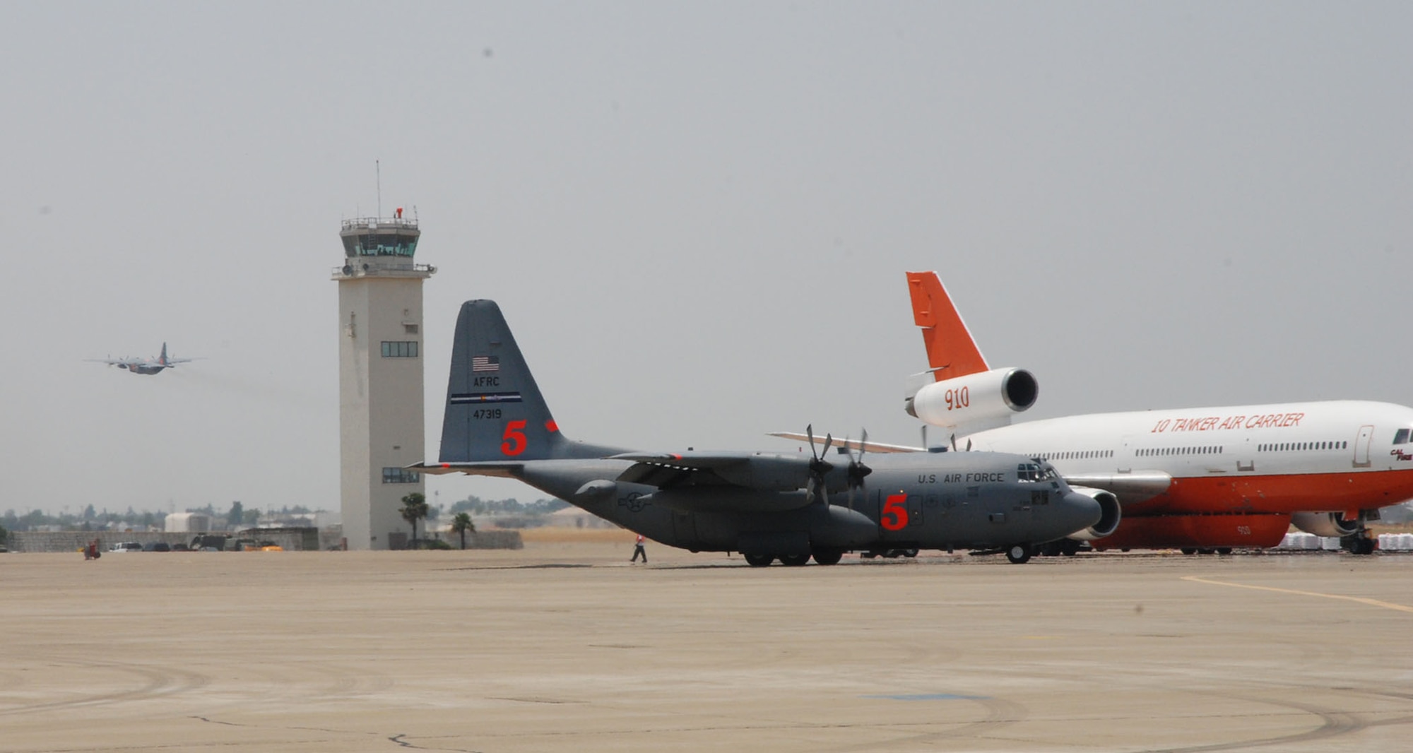 An Air Force Reserve Command C-130H deployed from the 302nd Airlift Wing, Peterson AFB, Colo., taxis toward the runway as another C-130 launches for a firefighting mission June 29 at McClellan Airfield in Sacramento, Calif. The aircraft are assigned to the 302nd Air Expeditionary Group that is fighting the Corral and Piute fires, each about 200 miles north and south of the California capital. As of 2:30 p.m. June 29, aircrews launched eight missions against the fires, dropping 24,000 gallons of fire retardant. The 302nd AEG includes the 302nd AW, and two Air National Guard units from the 153rd AW, Cheyenne, Wyo., and the 145th AW, Charlotte, N.C. (U.S. Air Force photo/Senior Airman Stephen Collier)
