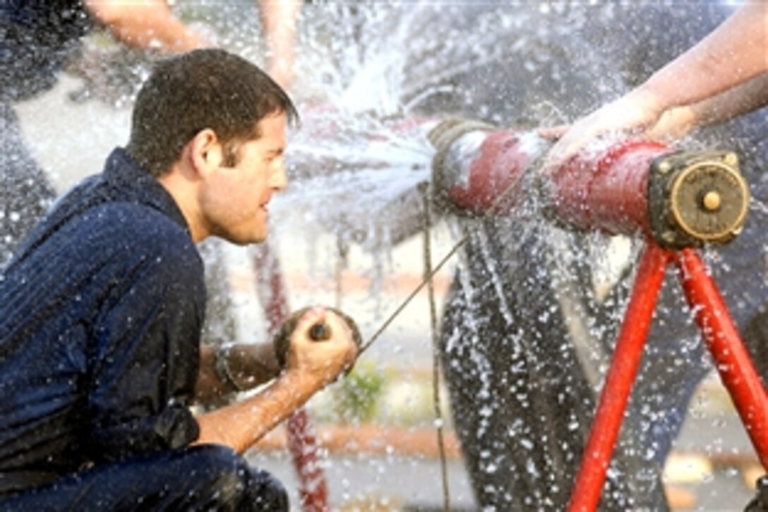 U.S. Navy Petty Officer 3rd Class John Ricker fights the clock and spraying water while trying to apply a marlin wrap to a ruptured pipe in the pipe patching event at the Damage Control Olympics aboard the USS Dwight D. Eisenhower, at port near the Navy's Farrier Fire Fighting School in Norfolk, Va., June 28, 2008. 