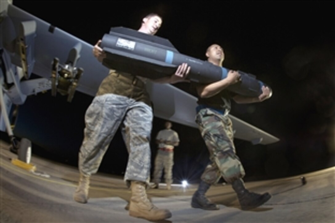 U.S. Air Force Tech. Sgt. Michael Stewart, left, and Senior Airman Valero Mendoza carry a practice AGM-114P Hellfire missile away from a MQ-9 Reaper at Creech Air Force Base, Nev., June 19, 2008.  