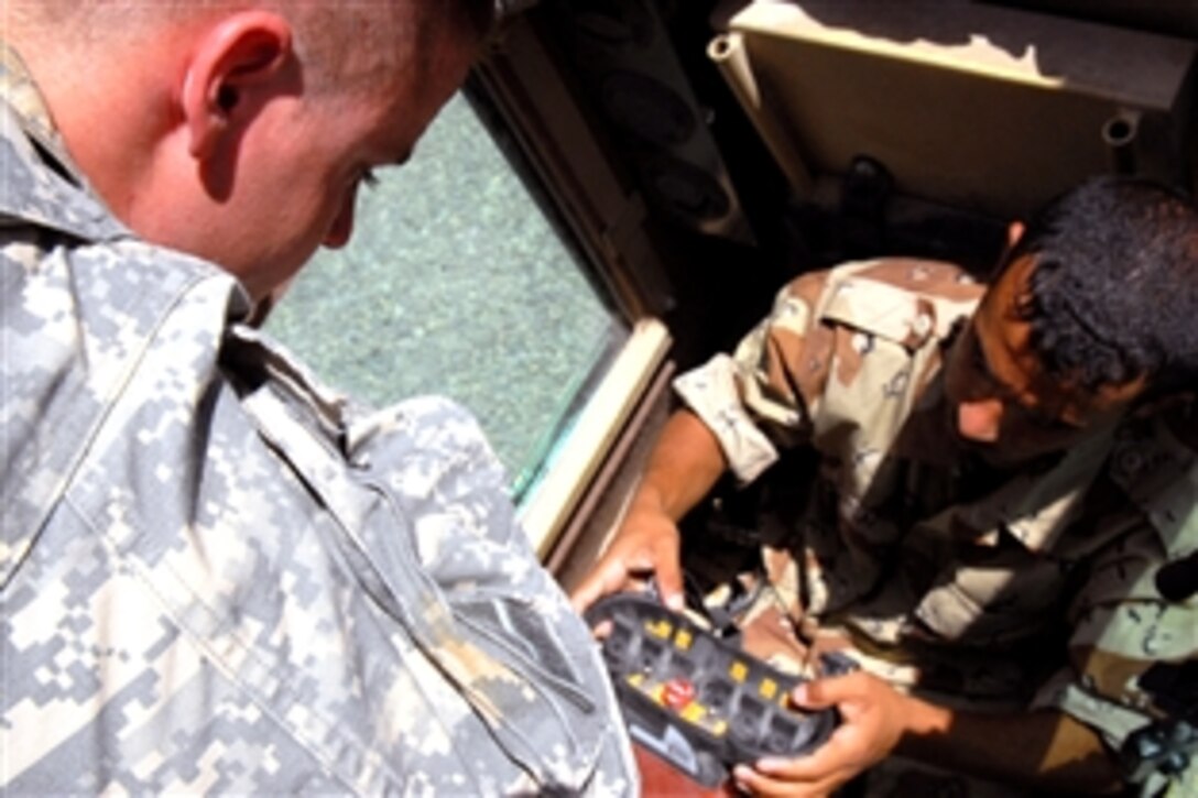 U.S. Army Spc. Jon Staib, a route clearance driver and gunner, trains an Iraqi army soldier to operate the controls of a husky engineer vehicle to lower and raise the arm and detonate possible improvised explosive devices during route clearance missions in a training exercise on a Contingency Operating Base Speicher, Tikrit, Iraq, June 26, 2008. Staib is assigned to the 326th Engineers Battalion, 58th Combat Engineers Company, 18th Engineer Brigade. 
