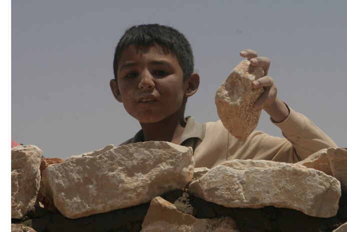 A young boy places a rock on the wall that will later be part of a new well in Dhramma, Iraq, June 29. Two wells will be built in each of the towns of Dhramma and Romalia that will provide the people there with free water.  Plans to build the wells were put together by Marines with Detachment 1, Civil Affairs Team 4, 2nd Battalion, 11th Marine Regiment, Regimental Combat Team 5. The wells are being built because the residents do not have an adequate source of water. ::r::::n::