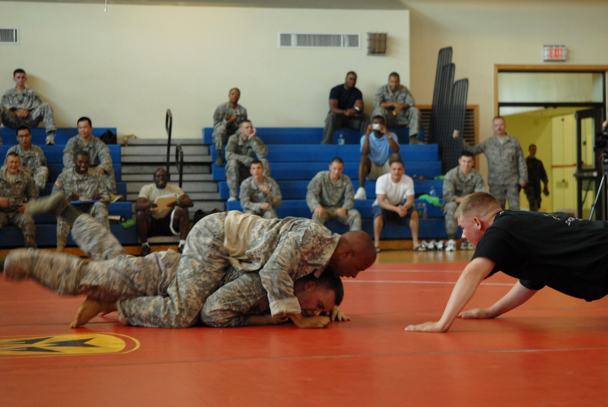 Army Spc. Derrick Royal,  Charlie / 1-44th Battalion, competes against Staff Sgt. Dustin Rieber, 8th Security Forces Squadron, while Army PFC John Carduff, a Modern Army Combative instructor, referees here June 27. Specialist. Royal and Sergeant Rieber have completed Level one of Modern Army Combative Training, required for all Soldiers and optional for Airmen. (U.S. Air Force photo by: Senior Airman Angela Ruiz)