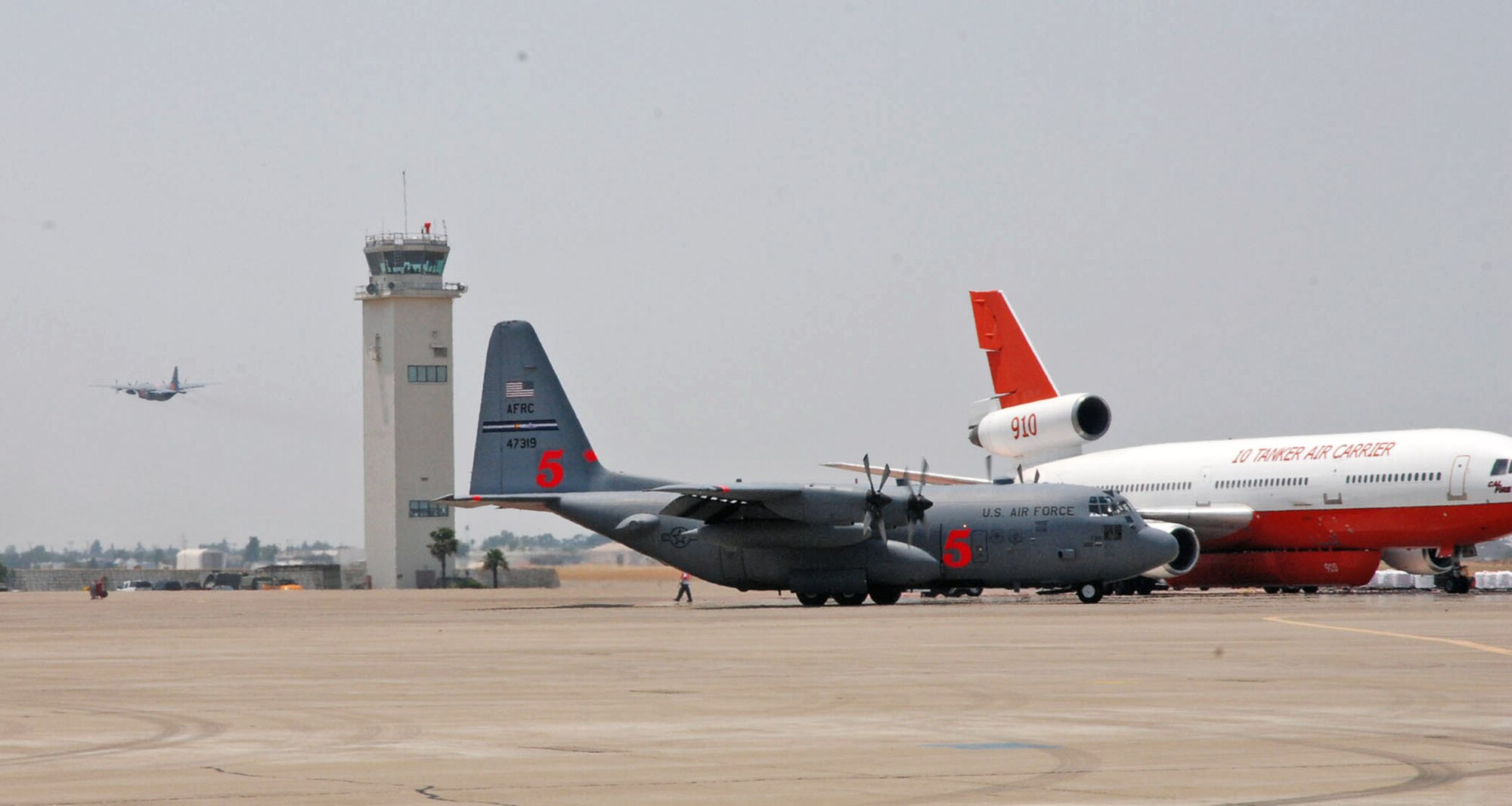 An Air Force Reserve Command C-130 Hercules taxies toward the runway as another C-130 launches for a firefighting mission June 29 at McClellan Airfield in Sacramento, Calif. The aircraft are deployed from the 302nd Airlift Wing, Peterson AFB, Colo., and assigned to the 302nd Air Expeditionary Group that is fighting the Corral and Piute fires in California. As of 2:30 p.m. June 29, aircrews launched eight missions against the fires, dropping 24,000 gallons of fire retardant. The 302nd AEG includes the 302nd AW, and two Air National Guard units from the 153rd Airlift Wing from Cheyenne, Wyo., and the 145th Airlift Wing from Charlotte, N.C. (U.S. Air Force photo/Senior Airman Stephen Collier) 
