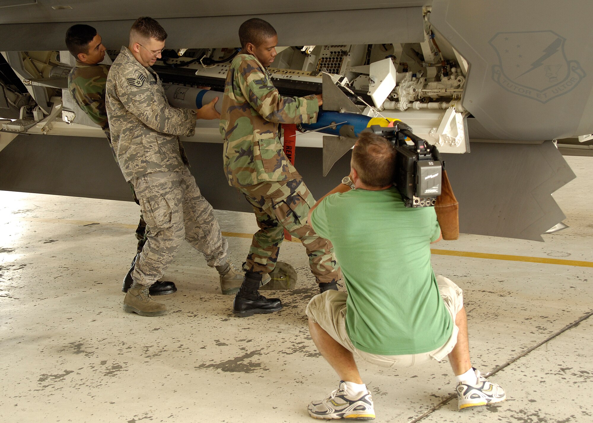 Mr. Mark Foerster, freelance cameraman, documents Airman 1st Class Reginald Jones, Staff Sgt. Brandon Schwendenman, and Airman 1st Class Robert Barboza, 49th Aircraft Maintenance Squadron, as they secure a missile to the F-22A Raptor at Holloman Air Force Base, N.M., on June 25. Mr. Foerster came to Holloman to film documentary segments about the F-22A Raptor and the QF-4 drone for Discovery Channel Canada's "Daily Planet" show. (U.S. Air Force photo/Airman 1st Class Michael Means)