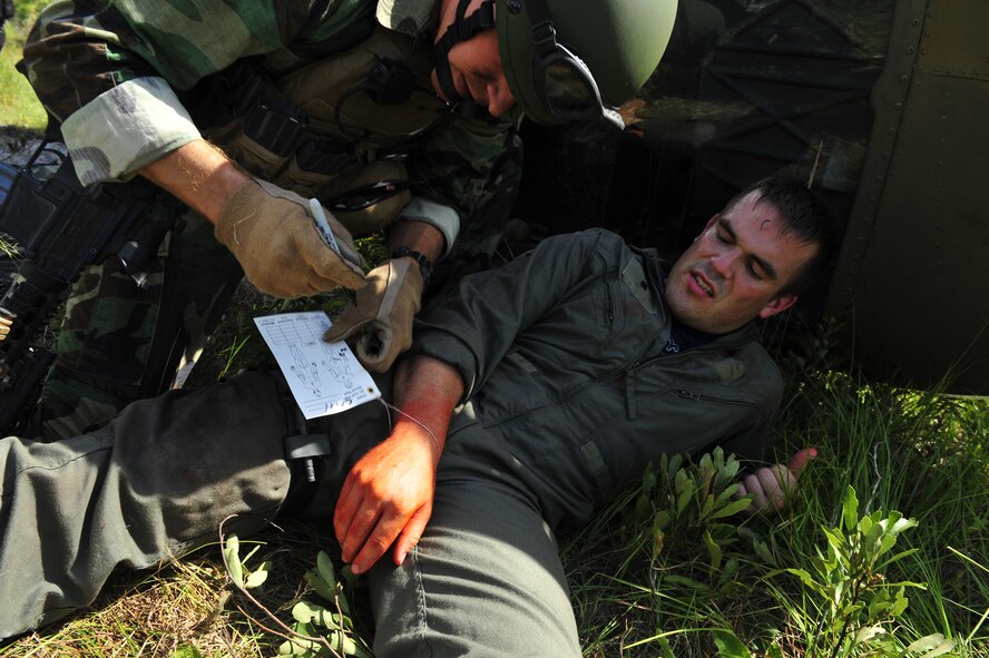 MOODY AIR FORCE BASE, Ga. -- Airman 1st Class Nathan Welu, 71st Rescue Squadron life support technician, simulates a gun shot wound to the leg while Staff Sgt. William Lawson, 38th Rescue Squadron pararescueman, writes down his vitals on a casualty information tag here June 27. This exercise was to access the 38th RQS pararescuemen's abilities to treat and evacuate casualties in the event of a real-world mass-casualty situation. (U.S. photo by Senior Airman Schelli Jones)