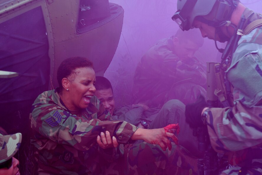MOODY AIR FORCE BASE, Ga. -- Tech. Sgt. Cynthia Wilson, 910th Medical Squadron optometry technician, Youngstown Air Reserve Station, Ohio, holds out her wounded hand while Senior Airman George Reed, 38th Rescue Squadron pararescueman, comes to her aid here June 27. Sergeant Wilson's injury simulated a cut-off finger during the mass casualty  exercise. (U.S. photo by Senior Airman Schelli Jones)