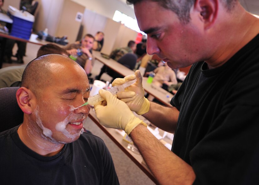 MOODY AIR FORCE BASE, Ga. -- Tech. Sgt. Robert Scott, 38th Rescue Squadron NCO-in-charge of medical readiness, moulages Staff Sgt. Victor Jeng, 41st Rescue Squadron aerial gunner, before a mass casualty exercise here June 27. Sergeant Scott injected vaseline under dried glue to give the effect of a blister from a burn. (U.S. Air Force photo by Senior Airman Elizabeth Rissmiller)