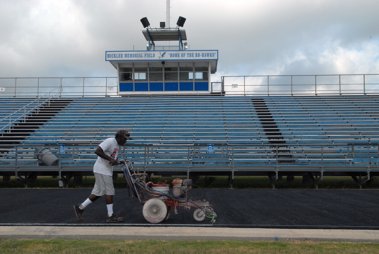 Rudy Roland, a 14-year employee with the Vibra-Whirl company, which is based in Panhandle, Texas, uses a machine to paint stripes on the new track surface at Randolph High School stadium. (U.S. Air Force photo by Rich McFadden)