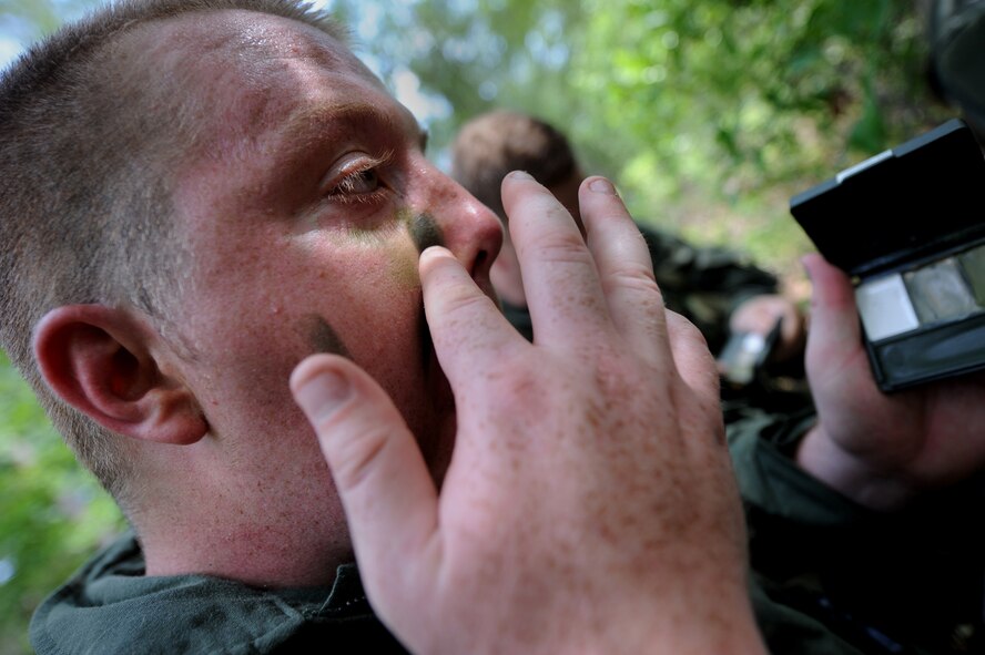 MOODY AIR FORCE BASE, Ga. -- Senior Airman George Horton, 41st Rescue Squadron flight engineer, puts on camouflage face paint to subdue flesh tones and make him less noticeable in his environment during survival, evasion, resistance, escape training here June 16. The SERE students tested their skills during an overnight training exercise at Grand Bay Range. (U.S. Air Force photo by Senior Airman Gina Chiaverotti) 
