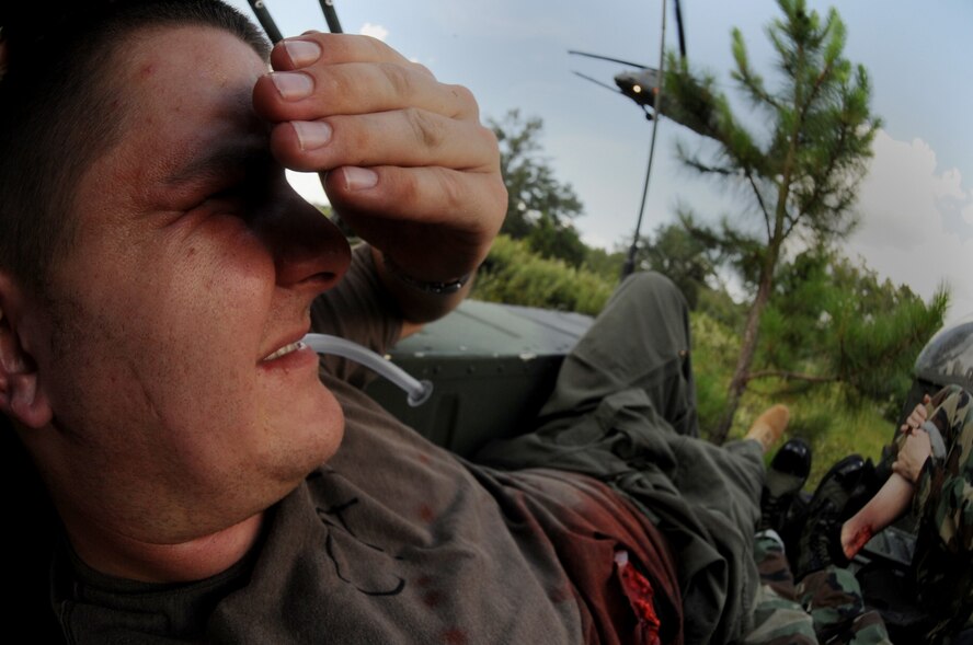 MOODY AIR FORCE BASE, Ga. -- Senior Airman Brent Fold, 71st Rescue Squadron life support technician, takes cover as an HH-60G Pave Hawk prepares to land at a mock helicopter crash site here June 27. Folds was playing an injured aircrew member during a mass casualty scenario that tested the skills of the 38th, 41st and 71st rescue squadrons. (U.S. Air Force photo by Senior Airman Gina Chiaverotti)