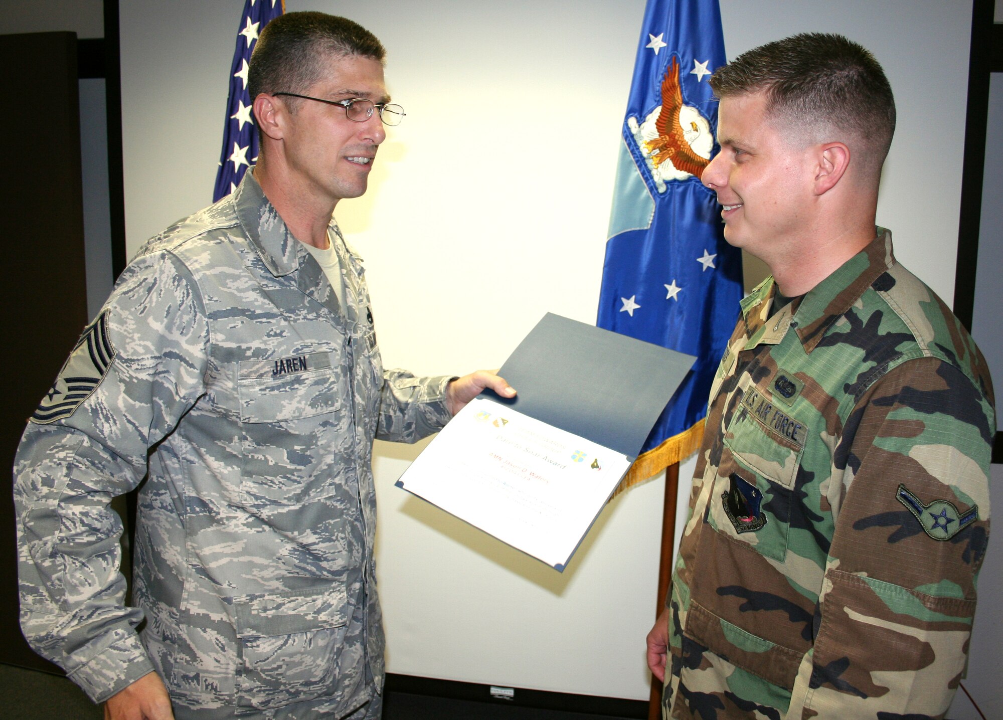 Airman Jason Waters (right), 412th Operations Group knowledge operations team information manager, receives the Dare to Soar award June 27 from Chief Master Sgt. Eric Jaren (left), 95th Air Base Wing acting command chief. Airman Waters received the award for being an active member of the Edwards community and for pursuing his Community College of the Air Force degree. The award is presented by the Chiefs Group to Airmen who go above and beyond in the performance of their duties. (Air Force photo by Chief Master Sgt. Luis Drummond) 