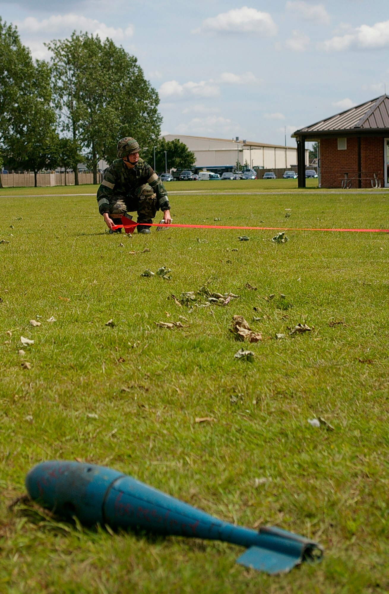 Senior Airman Joseph Symmonds, 100th Civil Engineer Squadron, cordons off the area around a simulated unexploded ordnance at Building 680 during Day 1 of an exercise at RAF Mildenhall, England, June 24. Throughout the day, several scenarios took place across the base to test response procedures. (U.S. Air Force photo by Karen Abeyasekere)