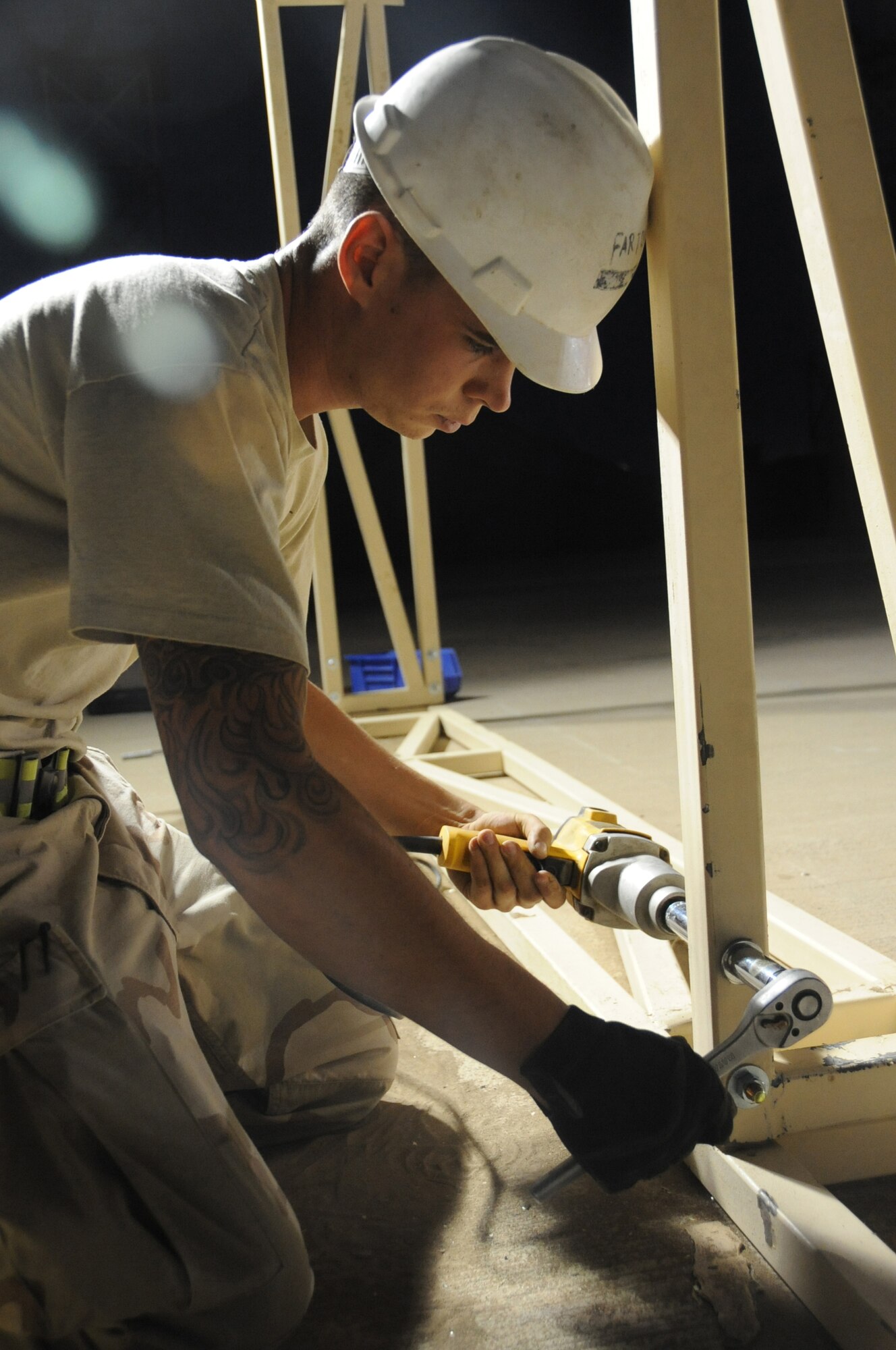 ALI BASE, Iraq -- Staff Sgt. Michael Pardue, 407th Expeditionary Civil Engineer structures team Airman, bolts the arch frame to the base of a 22X22 meter sun shade at the Alpha site during the evening hours to beat the 116 degree temperatures during the day. The shelter will be used to house the Predator MQ-1B Unmanned Aerial Vehicle that provides intelligence, surveillance and reconnaissance to coalition forces throughout Iraq. Sergeant Pardue is deployed from Eielson Air Force Base, Alaska. (U.S. Air Force photo/Tech. Sgt. Sabrina Johnson)