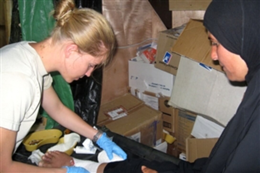 U.S. Army 1st Lt. Khara Keegan applies bandages to an Iraqi female burn patient at Convoy Support Center’s Smith Gate Burn Clinic in Scania, Iraq, June 23, 2008. Keegan is a security officer assigned to the 1st Squadron, 9th Cavalry Regiment.