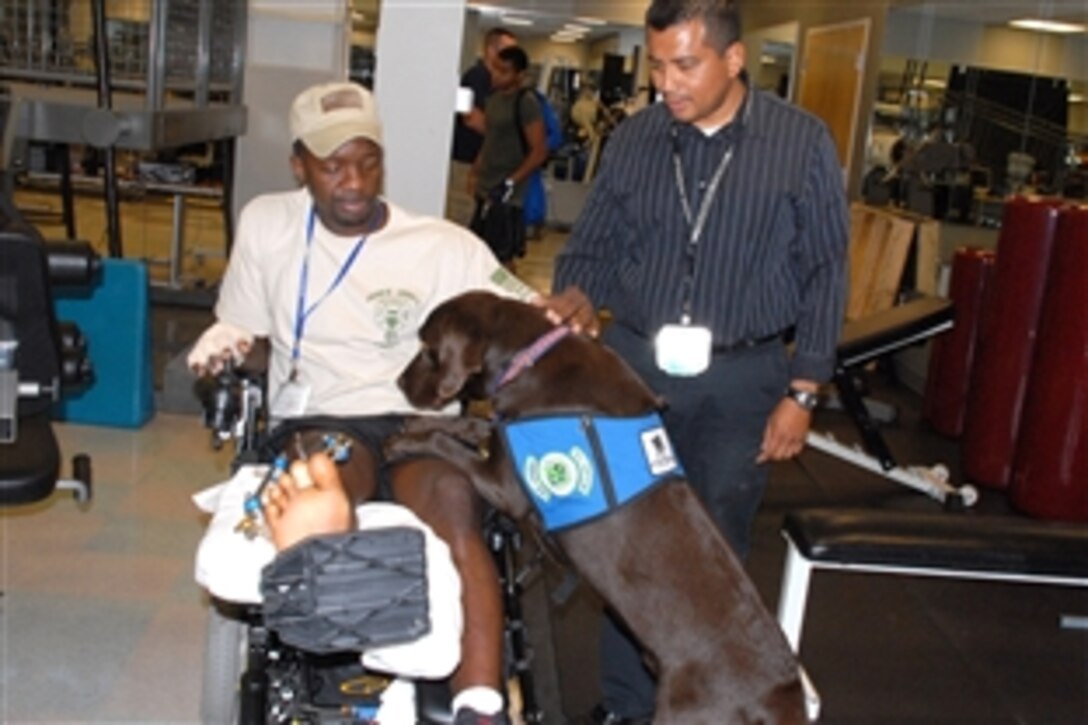 Deuce, a therapy dog at Walter Reed Army Medical Center, and his owner, Harvey Naranjo, greet U.S. Army Sgt. 1st Class Andrew R. Allman, a patient at the occupational therapy gym, June 27, 2008. 