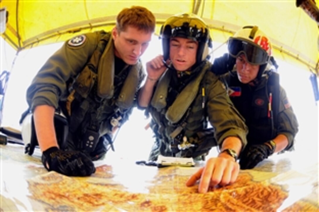 U.S. Navy Petty Officer 2nd Class Travis Story, left, Lt. Brandon Sheets and  Petty Officer 2nd Class Keith Holt  look over a map during a mission briefing at Iloilo Airport before their visit to remote locations on Panay Island that were hardest hit by Typhoon Fengshen, Iloilo, Philippines, June 30, 2008. The aircrew is assigned to the "Black Knights" of Helicopter Anti-Submarine Squadron 4, which is embarked aboard the aircraft carrier USS Ronald Reagan.  