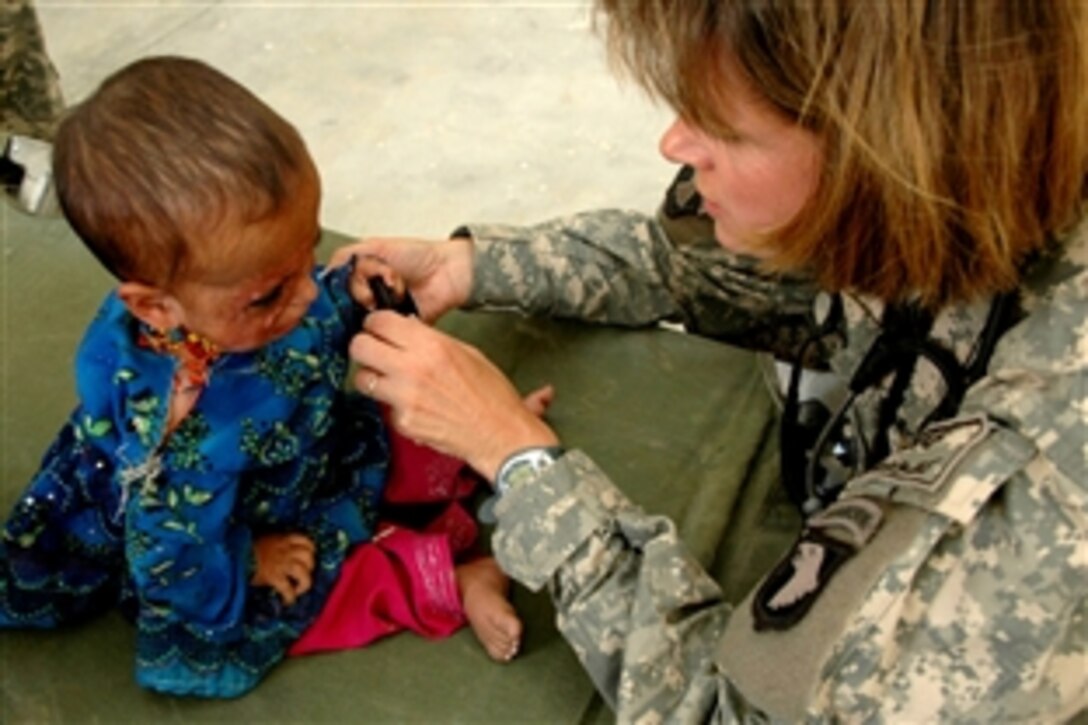 U.S. Navy Cmdr. Beth Myhre, the officer in charge of a cooperative medical assistance team, treats an Afghan baby girl for burn scars on her face as part of a medical outreach in Nilay Village in the Kohe Sofe District of Parwan, Afghanistan, June 26, 20886. 