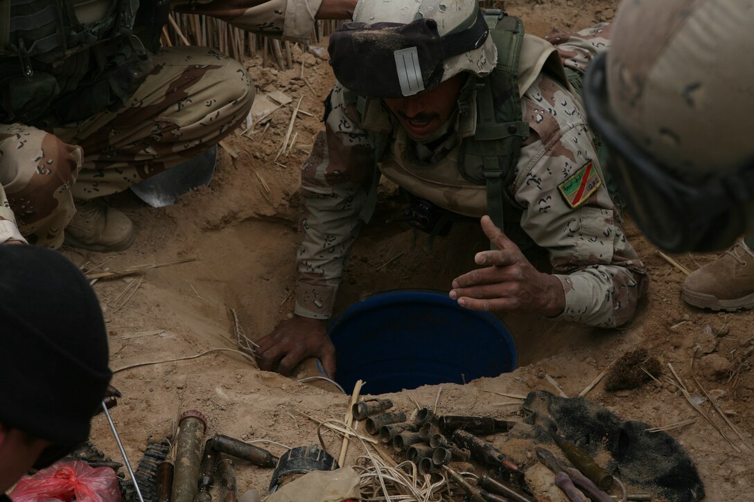 An Iraqi soldier from 3rd Battalion, 1st Brigade, 1st Iraqi Army Division pulls weapons, explosive material and documents from a cache found in an Al-Qaeda in Iraq safe-house in the Muthana district near Thar Thar Lake in Iraq.  The soldier was participating in Operation Lion?s Voice, an Iraqi-led mission to clear AQI out of the Muthana district.