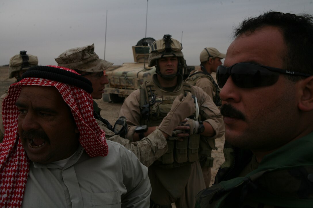 Lt. Col. Ahmed, the officer-in-charge of the Iraqis who participated in Operation Lion?s Voice, speaks to a resident of the Muthana district, while Johnathan Mozzen, a translator with 3rd Battalion, 1st Brigade, 1st Iraqi Army Division, tells 2nd Lt. Michael A. Phillips what the men are discussing.  Phillips was Ahmed?s adviser for Operation Lion?s Voice, and is also the intelligence adviser for 3-1/1?s Military Transition Team.