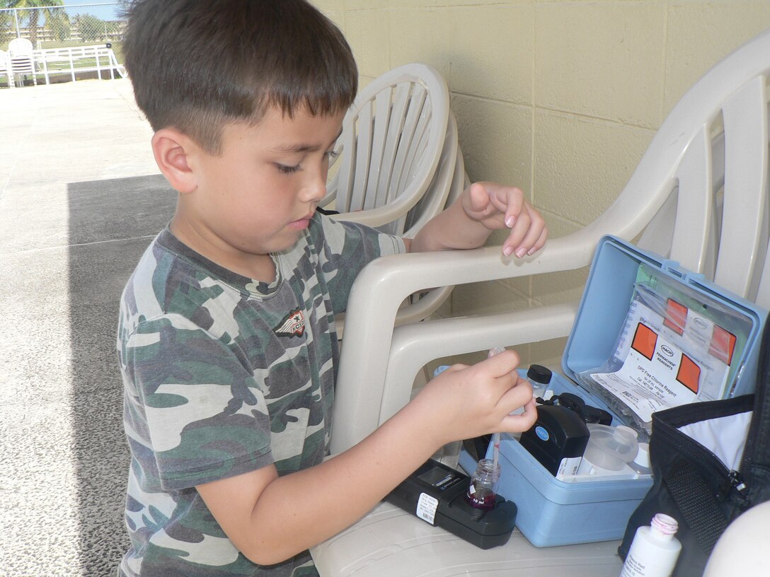 Micheal Rea, a second grader at Andersen Elementary School, samples water from the base pool recently. Micheal participated in Take Your Child to Work Day with his mother, Staff Sgt. Keumsuk Rea, 36th Medical Group.
