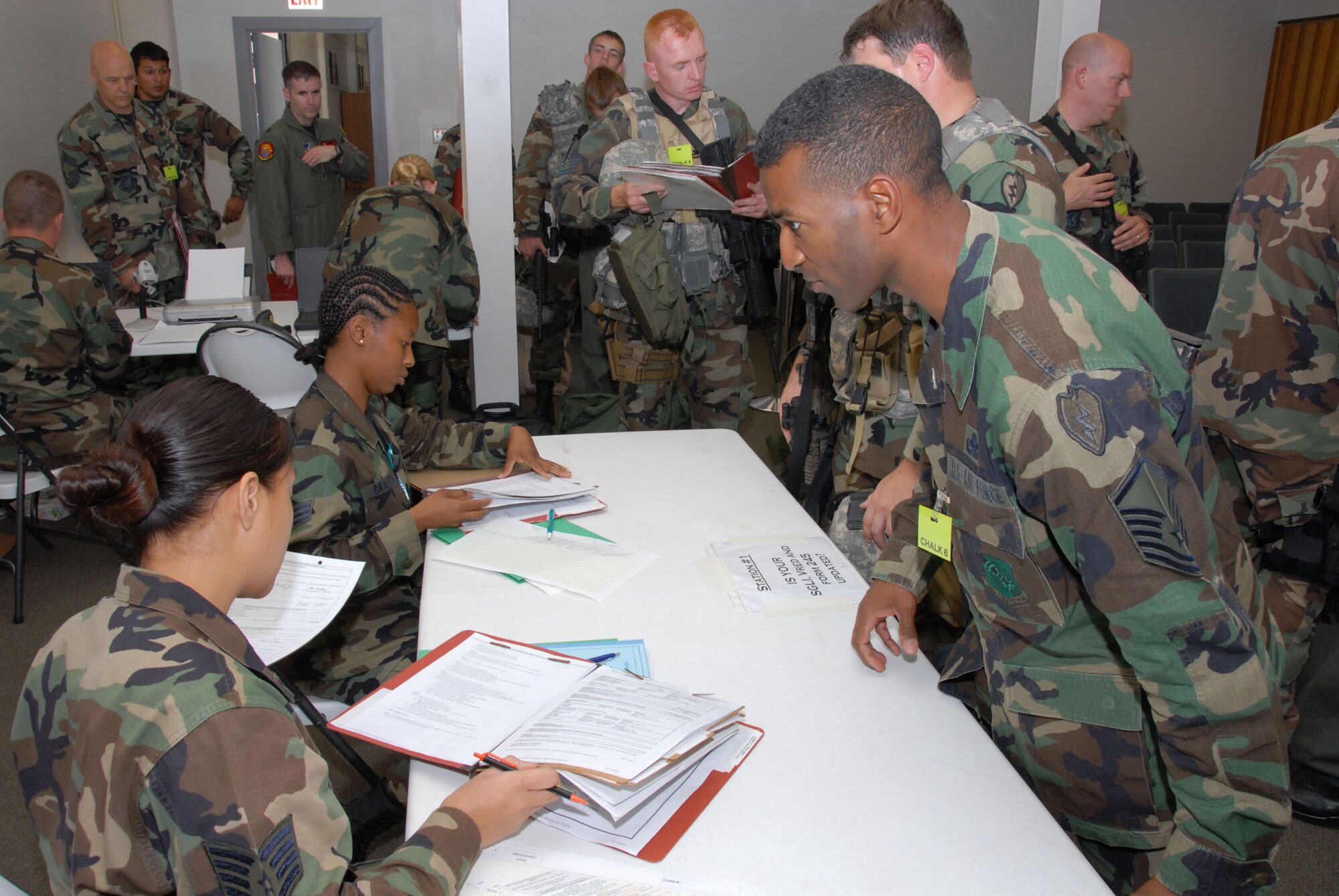 Staff. Sgt. Veronica Bastatas and Staff. Sgt. Patrice Brazzell inspect personnel folders as Master Sgt. Tireco Stinnette awaits clearnace to proceed through mobility processing lines during a recent exercise at Hickam at Hickam AFB, Hawaii. Photo by Ed Foster