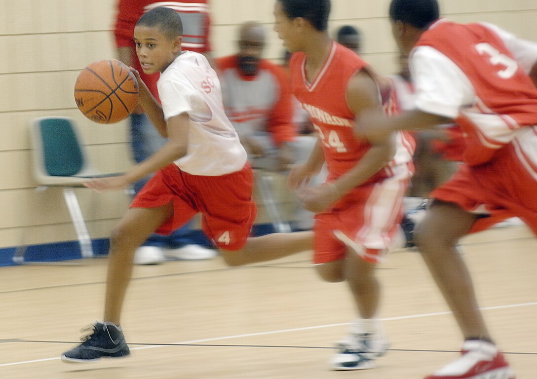 Joshua Scott, son of Master Sergeant retired, Victor Scott, dribbles past defenders of the Fort Monroe 11-12 year old basketball team  during a regular season game.  Joshua led the Rockets in points, but despite a valid effort, couldn't put the Rockets over the Fort Monroe team.  The Fort Monroe Youth won 25-20.  (U.S. Air Force photo/Senior Airman Vernon Young)
