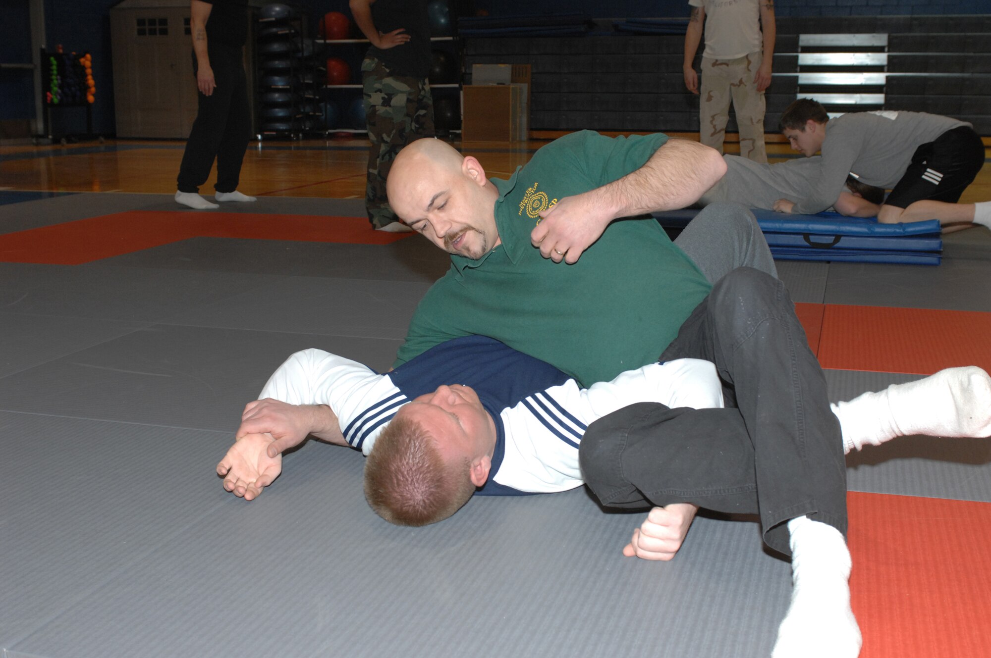 WHITEMAN AIR FORCE BASE, Mo. – Billy Matheny, a Ground Reaction And Self Protection Master Instructor, demonstrates a double shoulder lock on Officer Colt Callison, Chenega Company, that allows the officer to have a free hand to use his radio to call for assistance Feb. 19. The newly hired personnel received 70 hrs of training during covering pepper spray, authority & jurisdiction, legal use of force, weapons retention, handcuffing, DWI detection, search & seizure, installation entry controller duties and responsibilities installation, and entry requirements vehicle search techniques physical apprehension. (U.S. Air Force photo/Tech. Sgt. Samuel A. Park)
