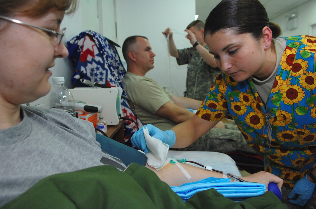 Staff Sgt. Amanda Winders checks on the platelet donation site of Army Capt. Susan Hawley to ensure the captain's blood is flowing properly while she donates life-saving blood products Jan. 28 at the Air Force Theater Hospital at Balad Air Base, Iraq. The platelet donation process takes about 90 minutes to complete. Though a time consuming process, many lives are saved by donations. Sergeant Winders is a 332nd Expeditionary Medical Support Squadron lab technician deployed from Wright Patterson Air Force Base, Ohio. Captain Hawley is a 546th Area Support Medical Company doctor deployed from Fort Hood, Texas. (U.S. Air Force photo/Senior Airman Julianne Showalter) 