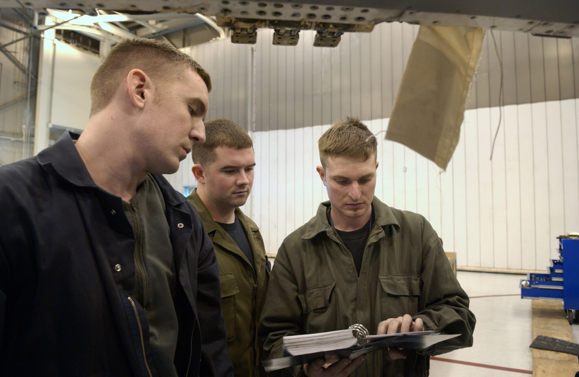 Staff Sgt. Jonathan Spencer, left, Staff Sgt. Mike Miller, center, and Staff Sgt. Robert McNiven refer to an Air Force technical manual while replacing a leading edge flap on an F-16 Fighting Falcon Feb. 28 at Eielson Air Force Base, Alaska. The flap enables F-16 maneuverability while in flight. After receiving the aircraft from Kunsan Air Base, Korea, Airmen of the 345th Aircraft Maintenance Squadron perform an inspection and replace parts that are worn or may cause future problems. The sergeants are crew chiefs assigned to the 354th AMXS. (U.S. Air Force Photo/Airman 1st Class Jonathan Snyder)