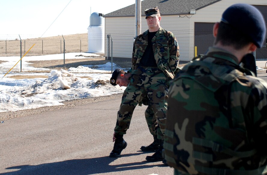 Airman 1st Class Brandon Blevins, 790th Missile Security Forces Squadron, searches Staff Sgt. Chad Thompson, 90th Space Wing, while Airman 1st Class Brett Ficek, 790th MSFS, maintains a watchful eye on the “suspect.” Sergeant Thompson played the role of an intruder during a training exercise at a missile alert facility. The exercise gave security forces Airmen training on detaining and searching a suspect (U.S. Air Force photo/Staff Sgt. John Hamilton).