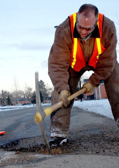 Brian Galles, 90th Civil Engineer Squadron, preps a pot hole on 10th Calvary Ave. Feb. 14 for repair. The patch is a temporary solution until an asphalt plan is activated in the spring (U.S. Air Force photo/Airman 1st Class Daryl Knee).
