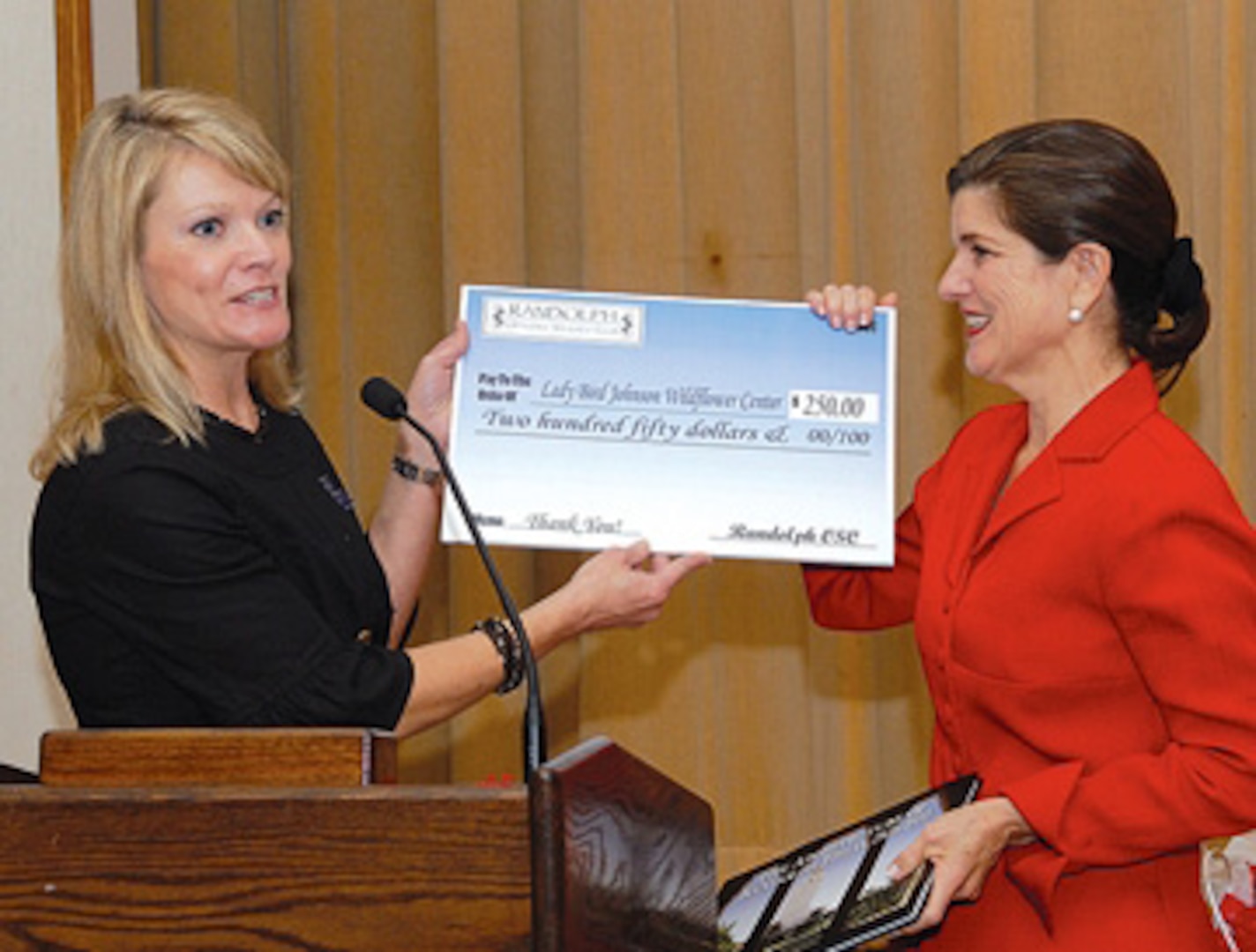 Jennifer Pleus (left), president of the Randolph Officers’ Spouses’ Club, presents Luci Baines Johnson, daughter of President Lyndon Baines Johnson, with a monetary donation to the Lady Bird Johnson Wildflower Center in Austin. Ms. Johnson spoke to club members during a luncheon Feb. 21 at the officers’ club. Photo by Rich McFadden